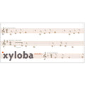 Sheet music page for xylophone melodies, featuring three staffs with musical notes and titles including 'when the Saints', 'Silent Night', and 'Sur le point d'Aspieux'. The word 'xyloba' appears prominently in large gray letters across the bottom, with a small orange dot near the left edge.