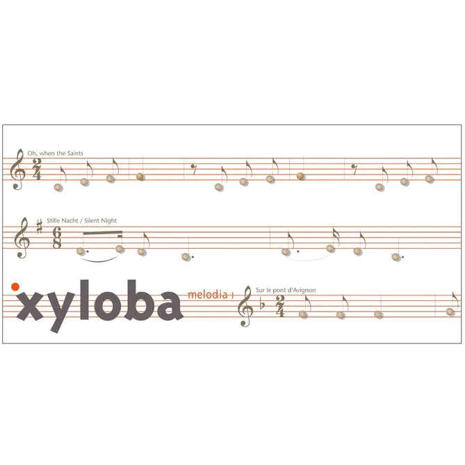Sheet music page for xylophone melodies, featuring three staffs with musical notes and titles including 'when the Saints', 'Silent Night', and 'Sur le point d'Aspieux'. The word 'xyloba' appears prominently in large gray letters across the bottom, with a small orange dot near the left edge.