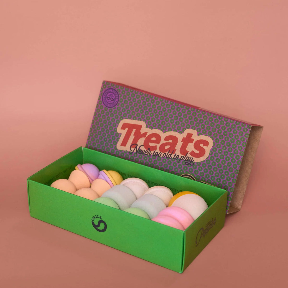 Box of colorful bath bombs with a 'Treats' label on a pink background