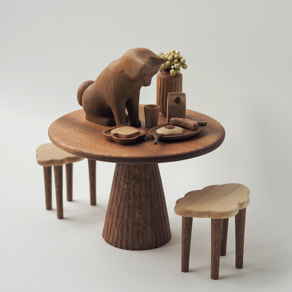 Wooden table with a bear sculpture and stools on a light gray background
