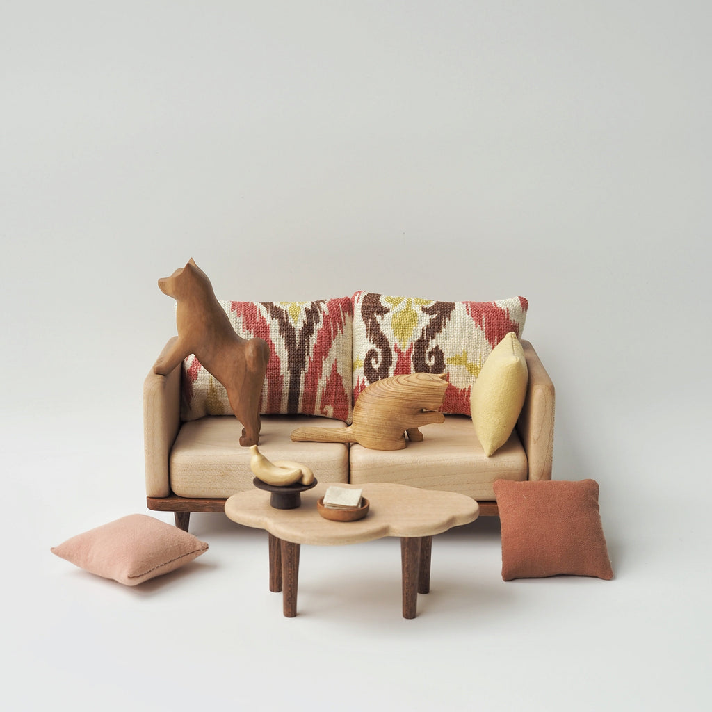 Sofa with decorative pillows and a small table on a plain background