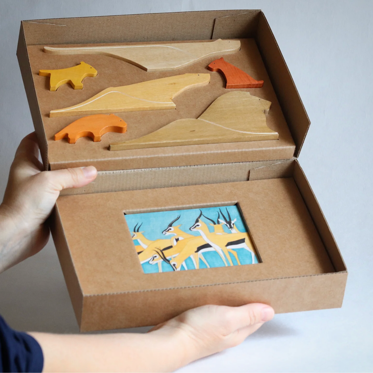 Wooden toy track set in a cardboard box held by a person